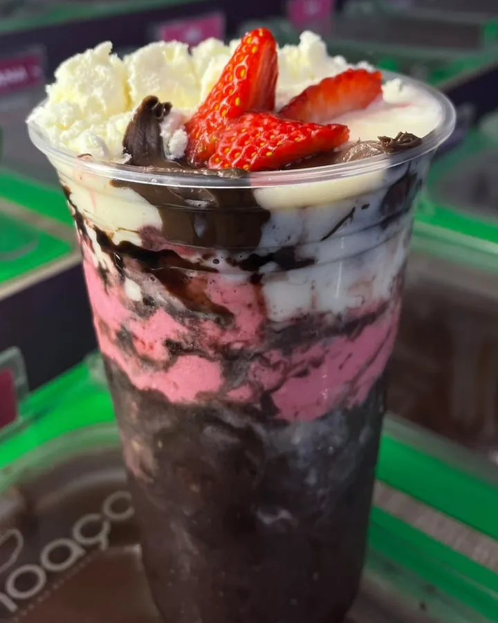 Copo de açaí em camadas com creme de morango, calda de chocolate e morangos frescos